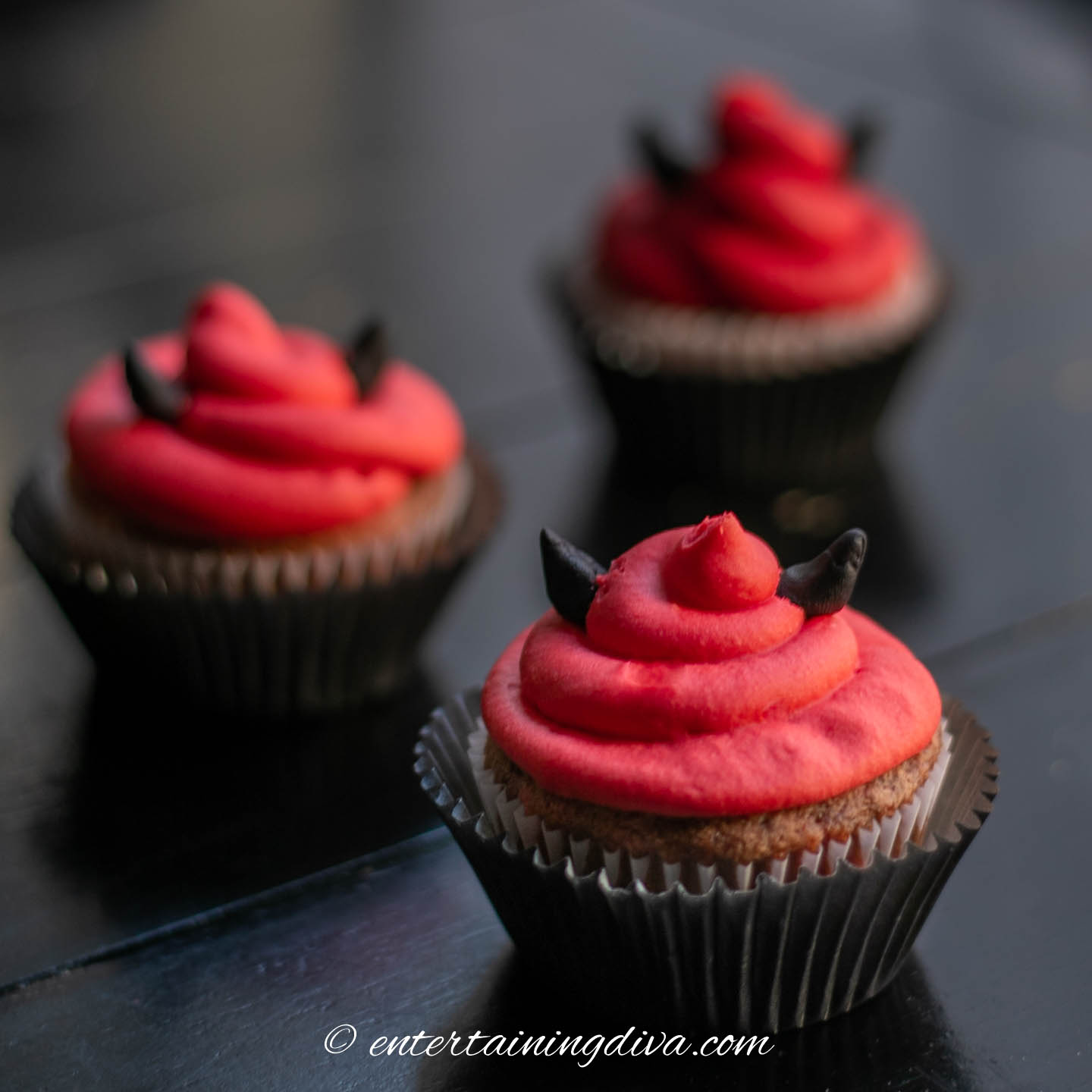 Three devilish red velvet Halloween cupcakes on a table