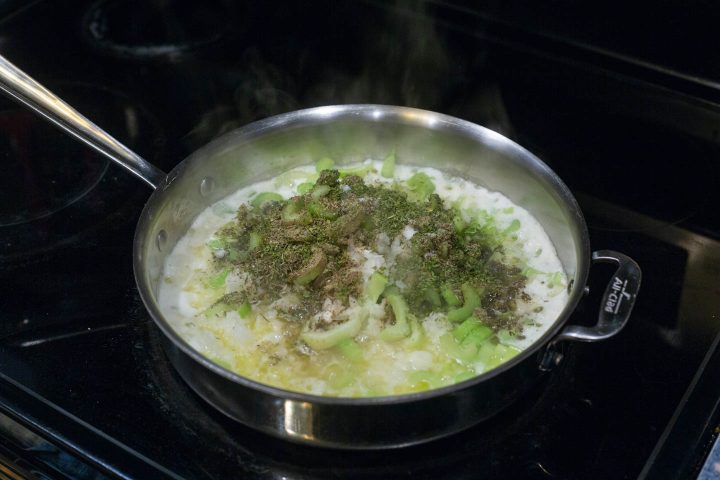 Celery, onions and spices being cooked in butter in a saute pan