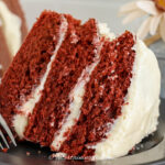 a slice of red velvet cake with traditional frosting