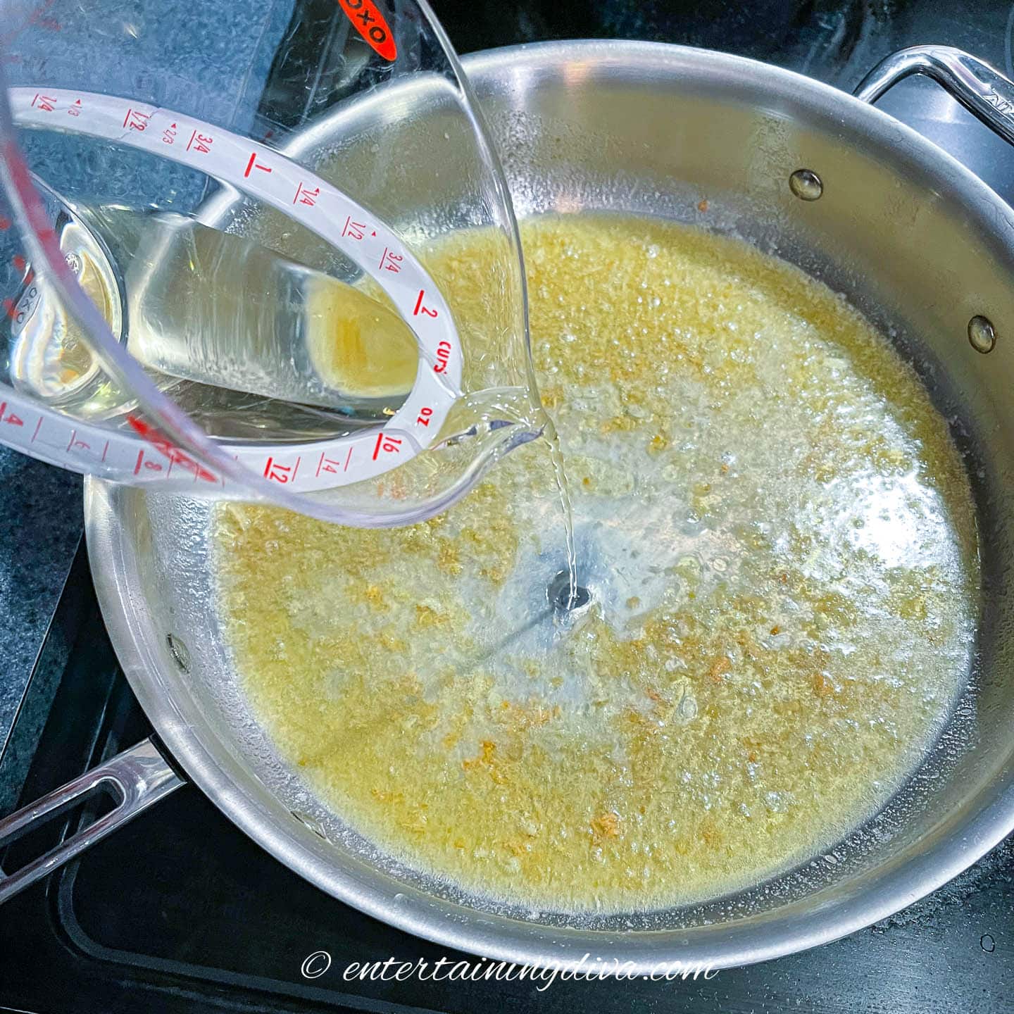 Wine pouring into saucepan with butter and garlic