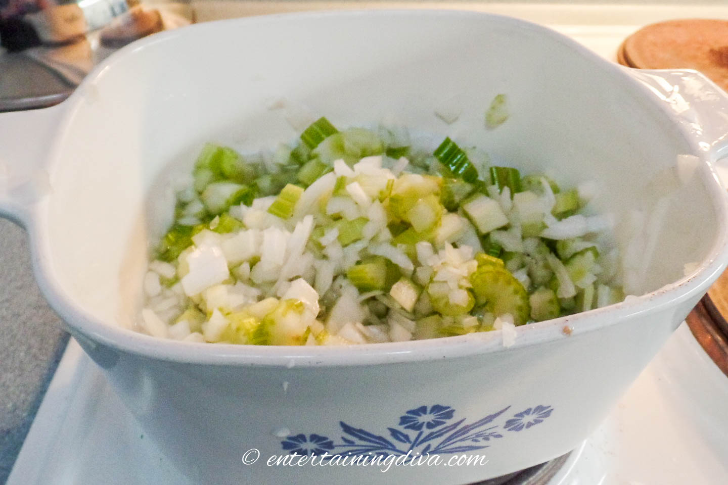 chopped onions and celery in a glass baking dish