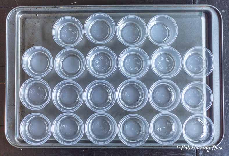Jello shot cups spread out on cookie sheet waiting for white pina colada jello shot mix