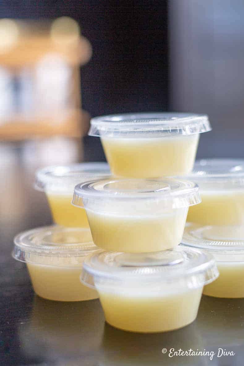 a stack of white pina colada jelly shots in shot cups with lids