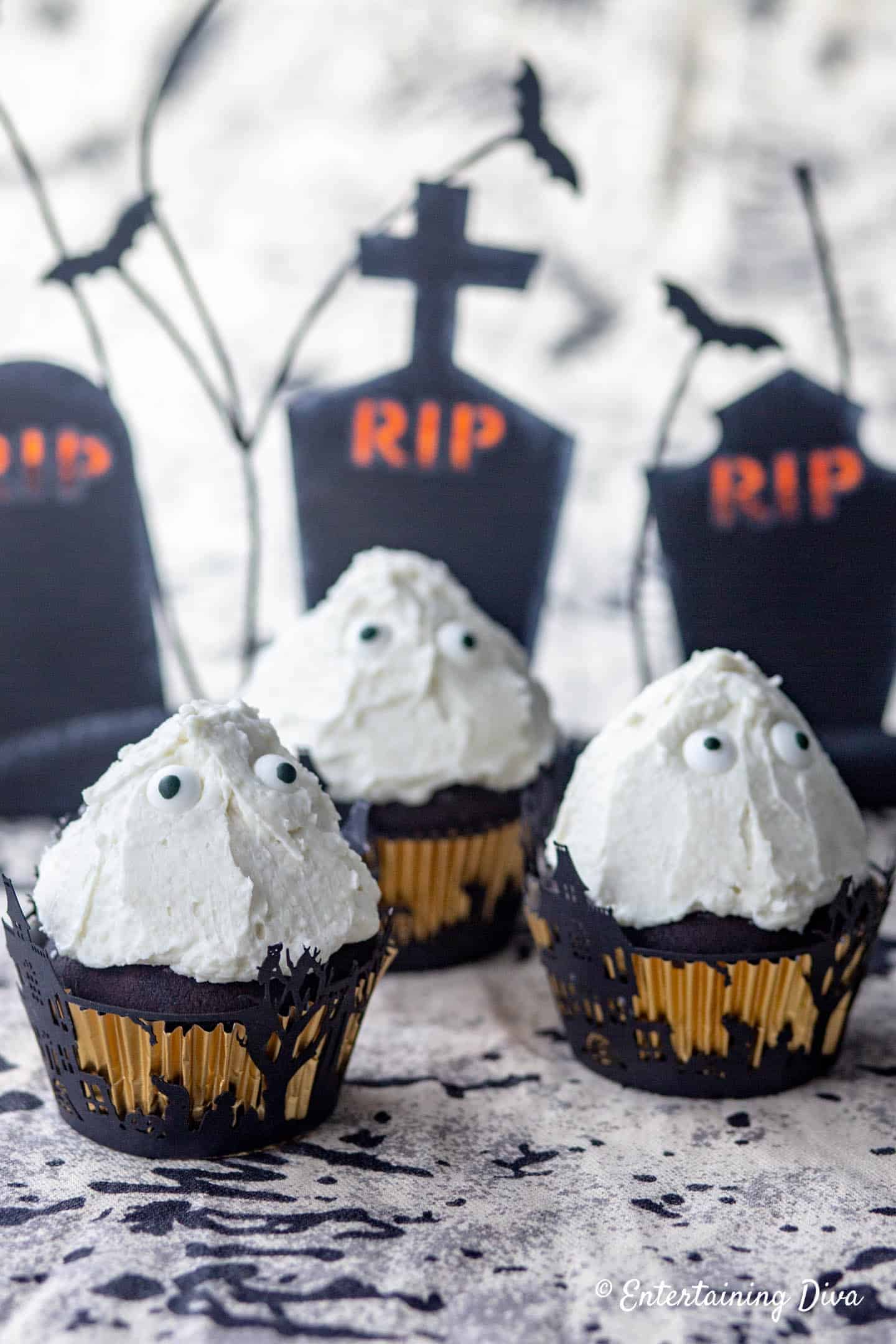 3 ghost Halloween cupcakes in front of Halloween tombstones