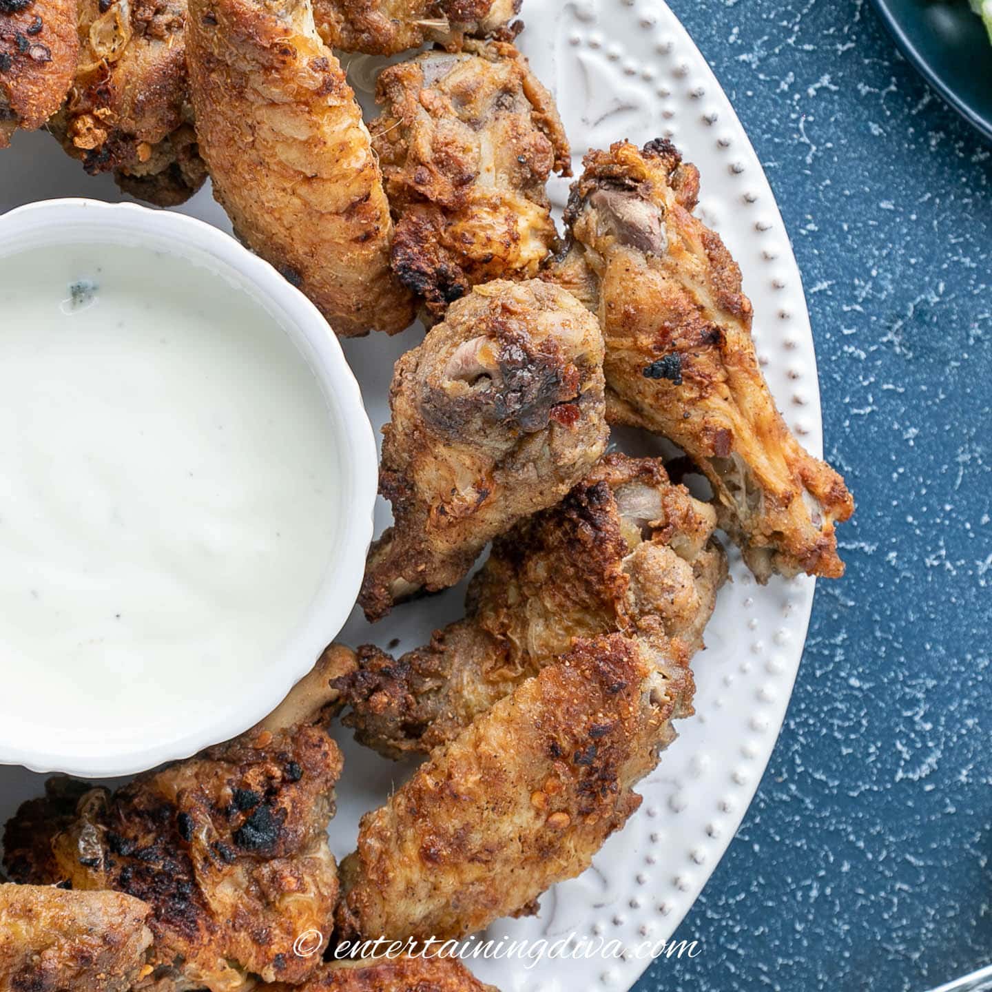 a plate of marinated spicy chicken wings with blue cheese dressing on the side