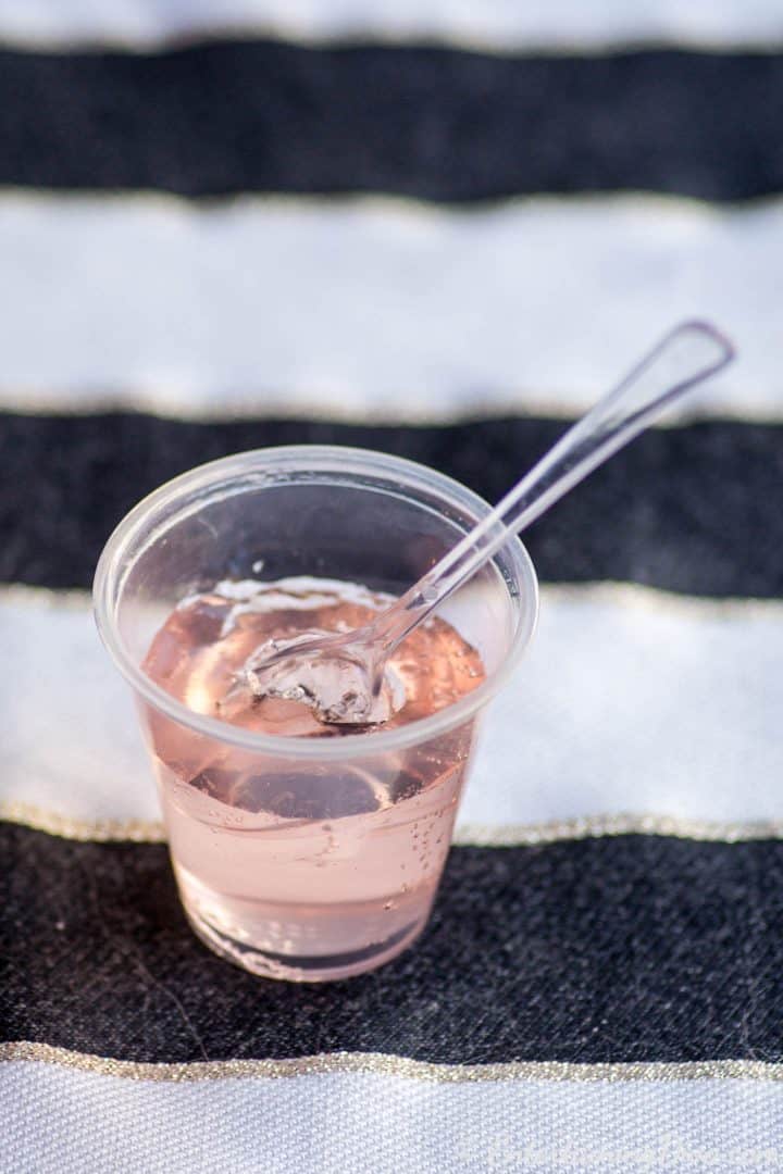 Pink champagne jello shot in a jello shot cup served with a mini spoon