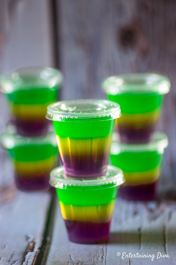 Purple, gold and green Mardi Gras jello shots in jello shot cups with lids
