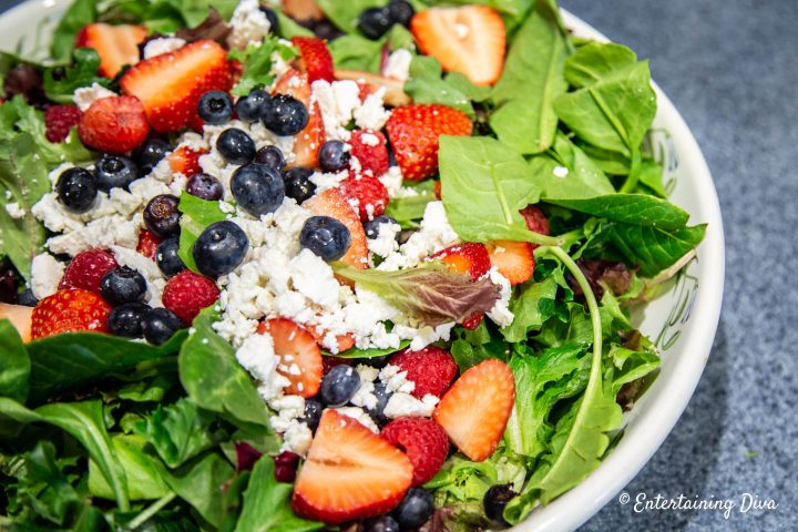 Salad made with strawberries, blueberries, raspberries and goat cheese on mixed greens