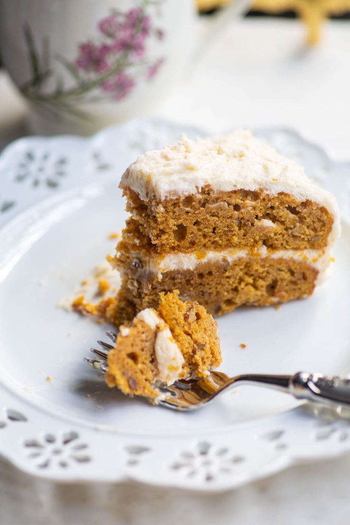 Pumpkin spice layer cake with cream cheese icing on a plate with a bite out of it