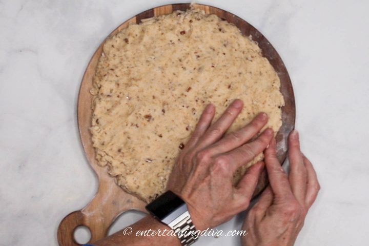 Scones dough being patted out to form a circle on a cutting board