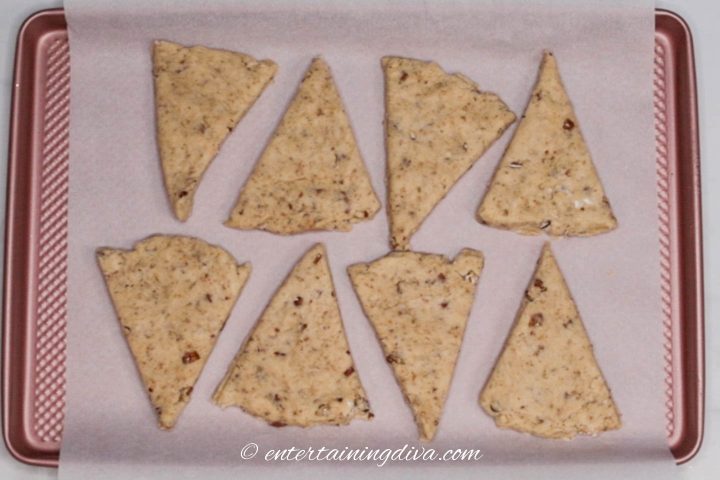 Maple pecan scones wedges on a cookie sheet with parchment paper