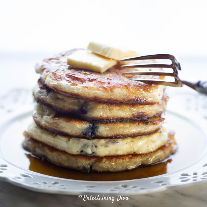 A stack of blueberry buttermilk pancakes being cut with a fork