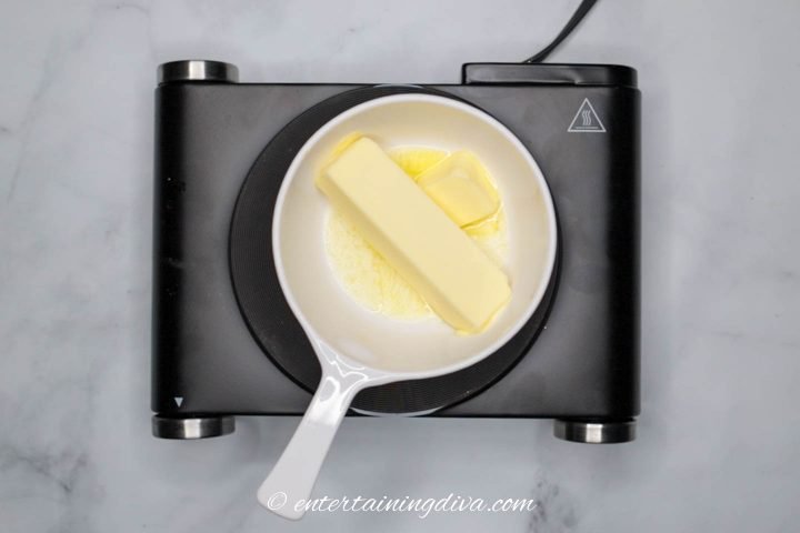 Butter being melted in a small pan on a stove element