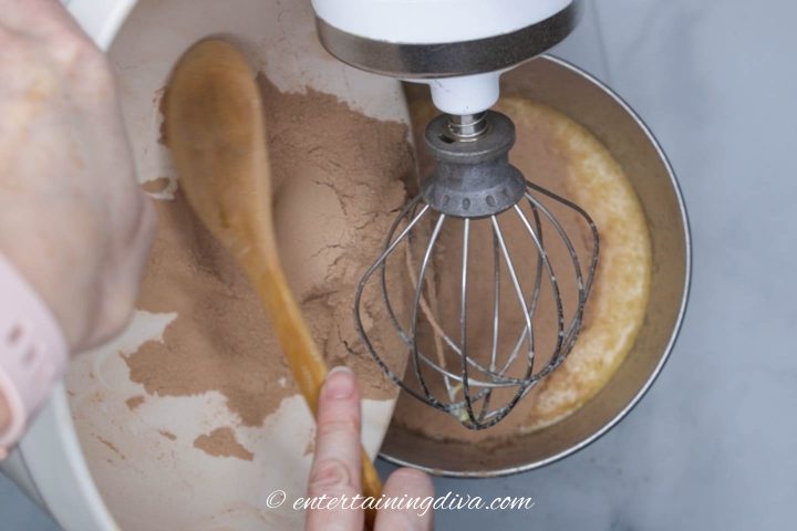 Chocolate cupcake dry ingredients being added to the wet ingredients in a mixing bowl