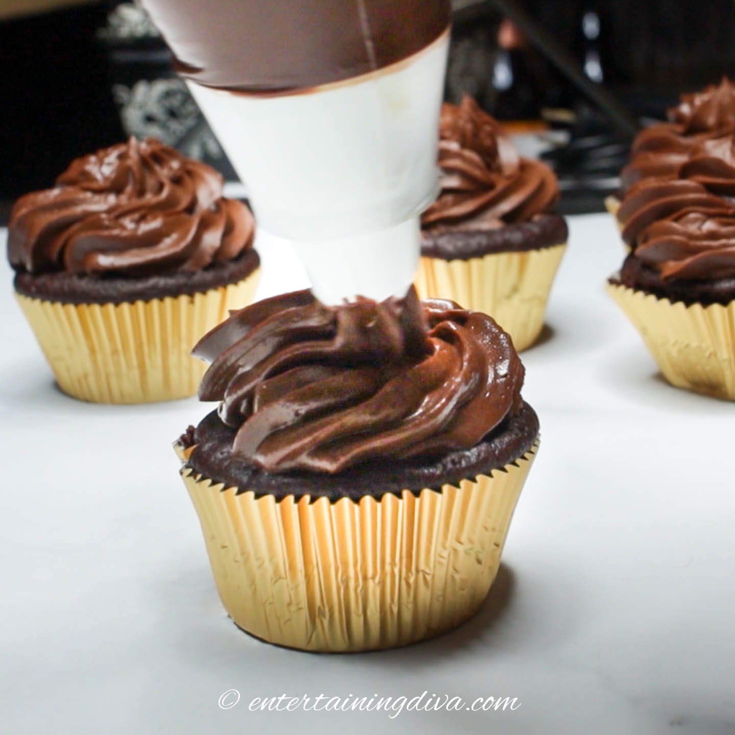 Chocolate icing being piped onto a cupcake