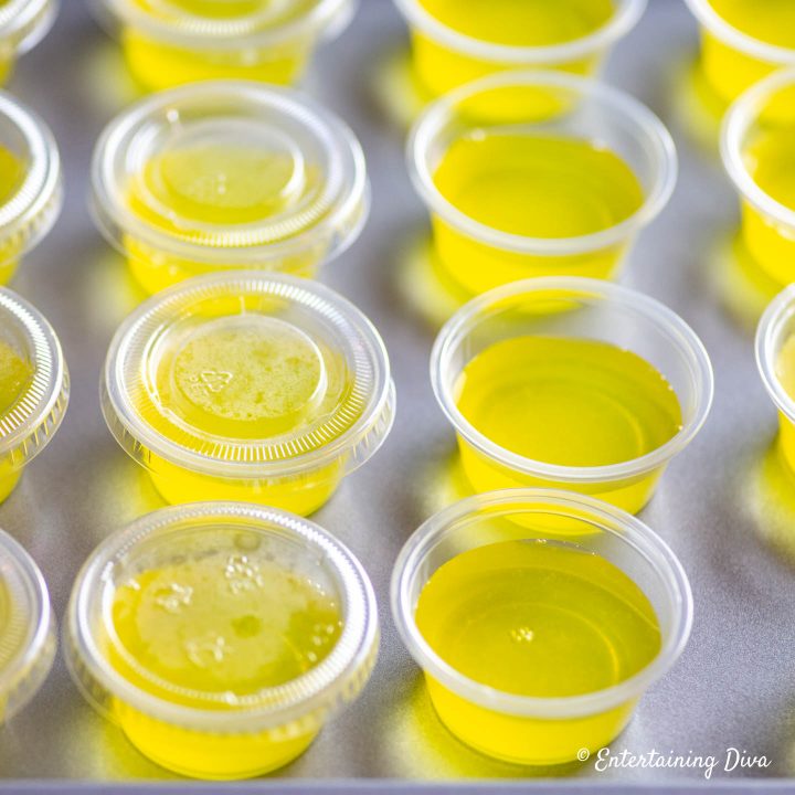 Yellow jello shots in jello shot cups, some with lids and some without