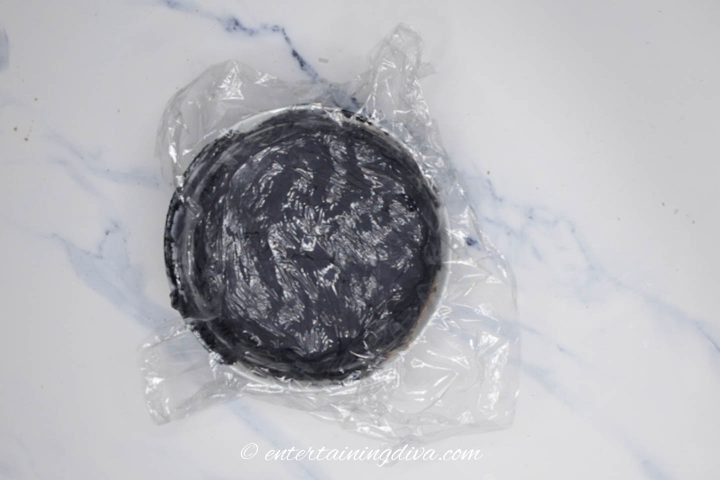 black royal icing covered with plastic wrap ready to be stored