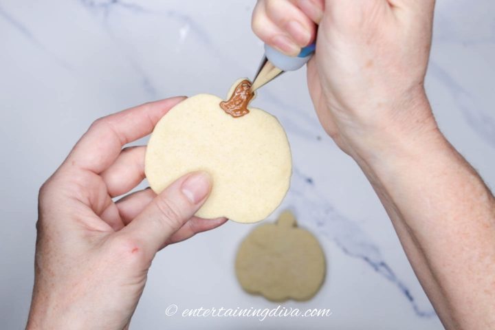 brown royal icing stem piped on a pumpkin cookie