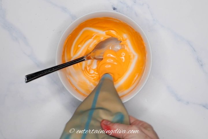 Orange icing being added back into the bowl for storage