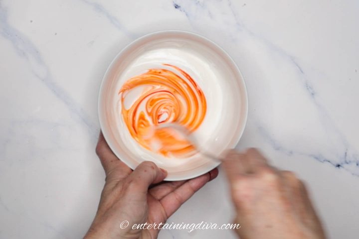 Orange royal icing being mixed