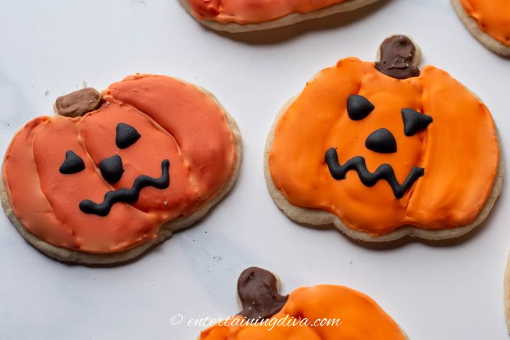 Decorated pumpkin cookies made with homemade orange food coloring and AmeriColor Orange food coloring