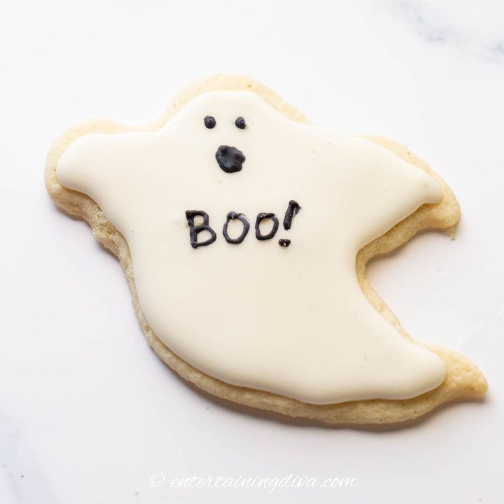 ghost cookie decorated with white royal icing and black eyes and mouth