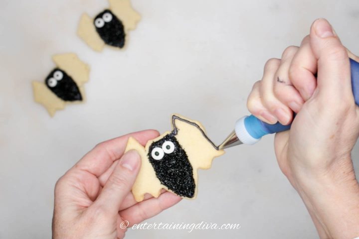 Wings of the bat cookie being outlined with black royal icing