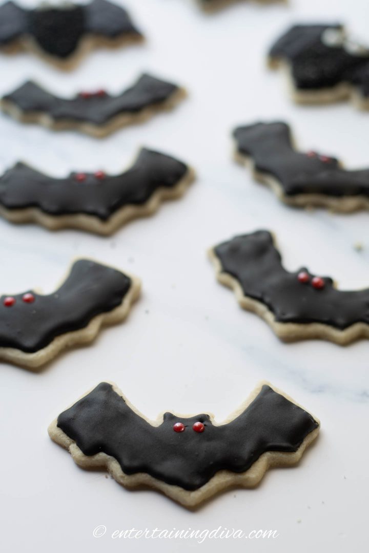 Halloween bat sugar cookies decorated with black royal icing and red sugar pearl eyes