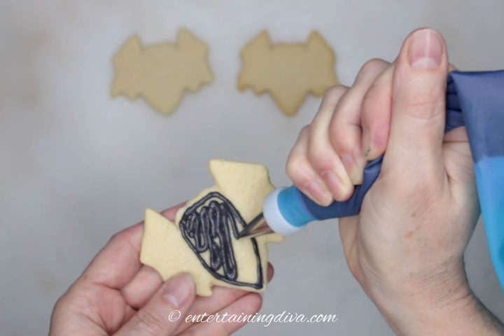 Center of the bat cookie being flooded with black royal icing