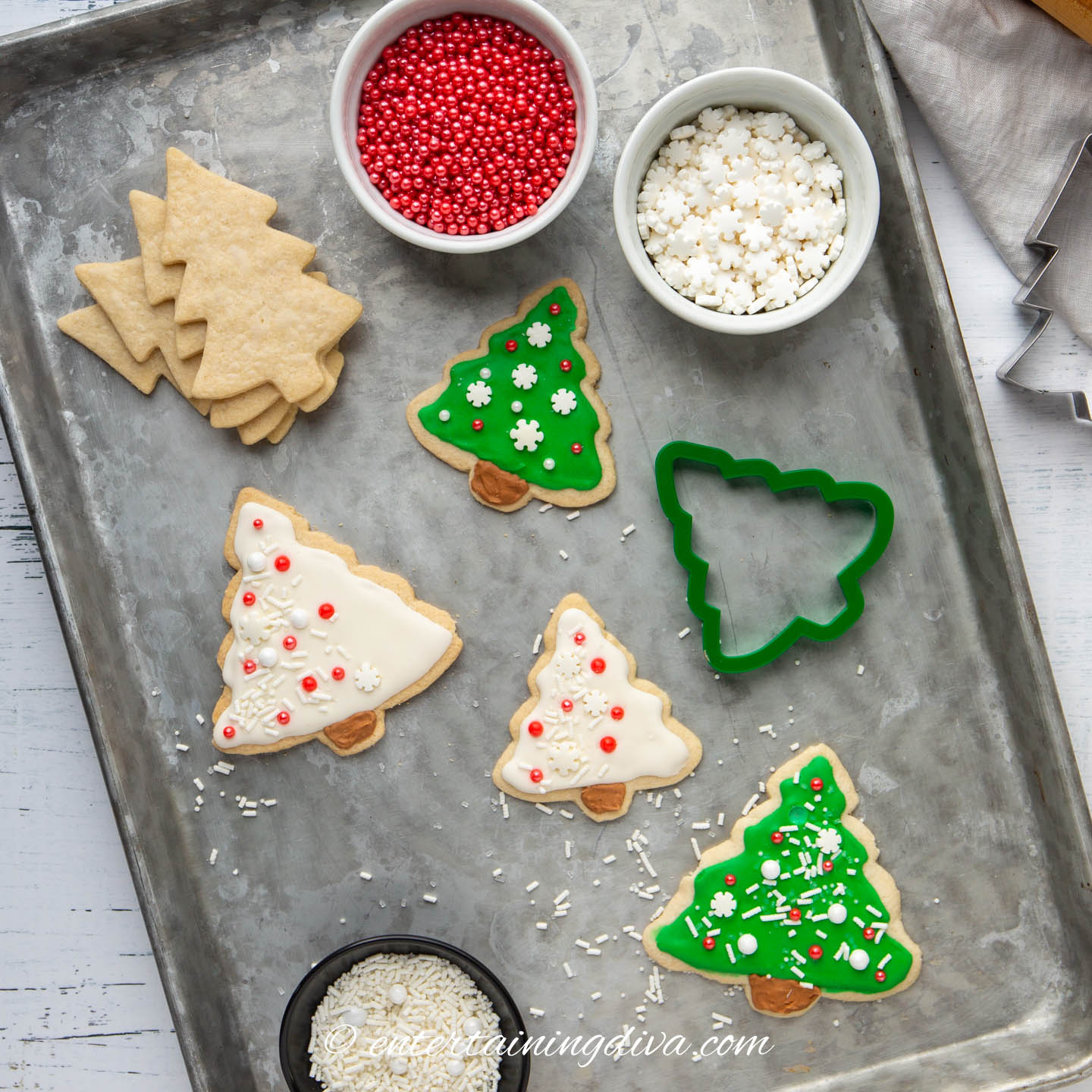 Three different Christmas tree sugar cookie designs on a baking sheet.