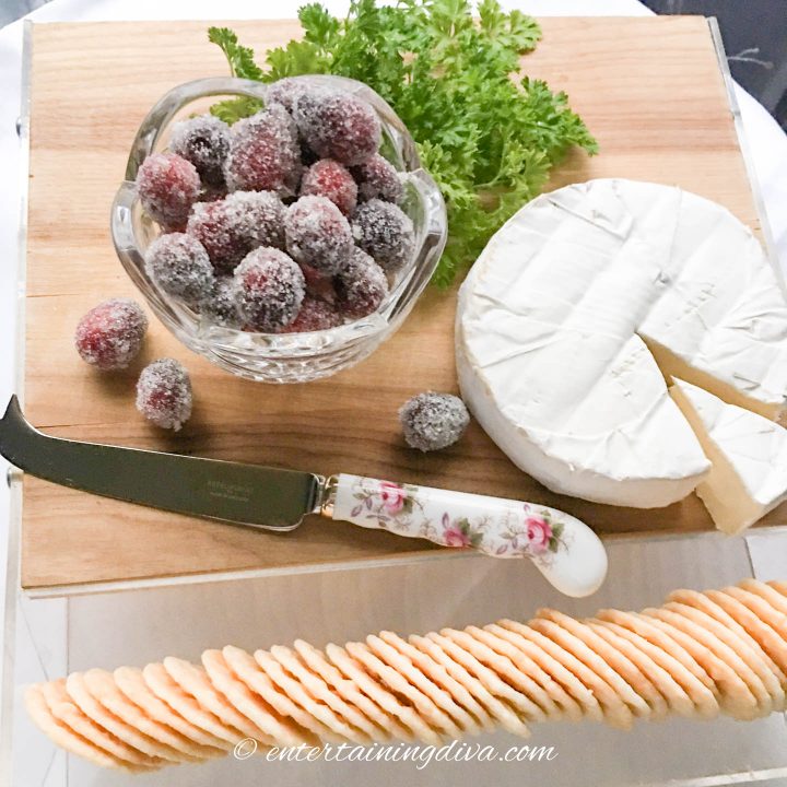 sparkling sugared cranberries on a cheese board with brie and some crackers