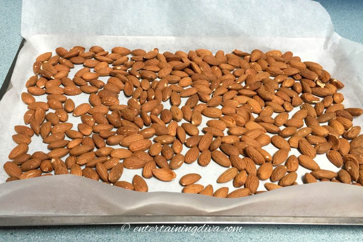 Almonds spread out on a parchment-lined cookie sheet