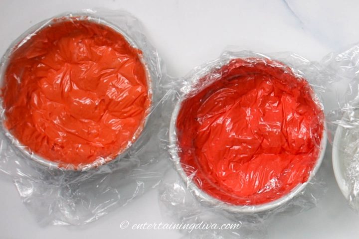 Tulip Red royal icing and Red Red royal icing in small bowls covered with plastic wrap