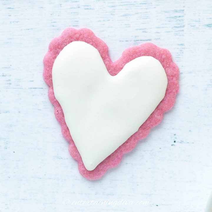 Heart cookie made from a pink sugar cookie with white royal icing