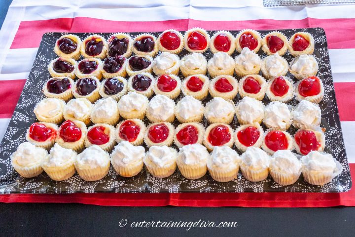 Blueberry, whipped cream and cherry toppings on mini cheesecake tarts in an American flag design