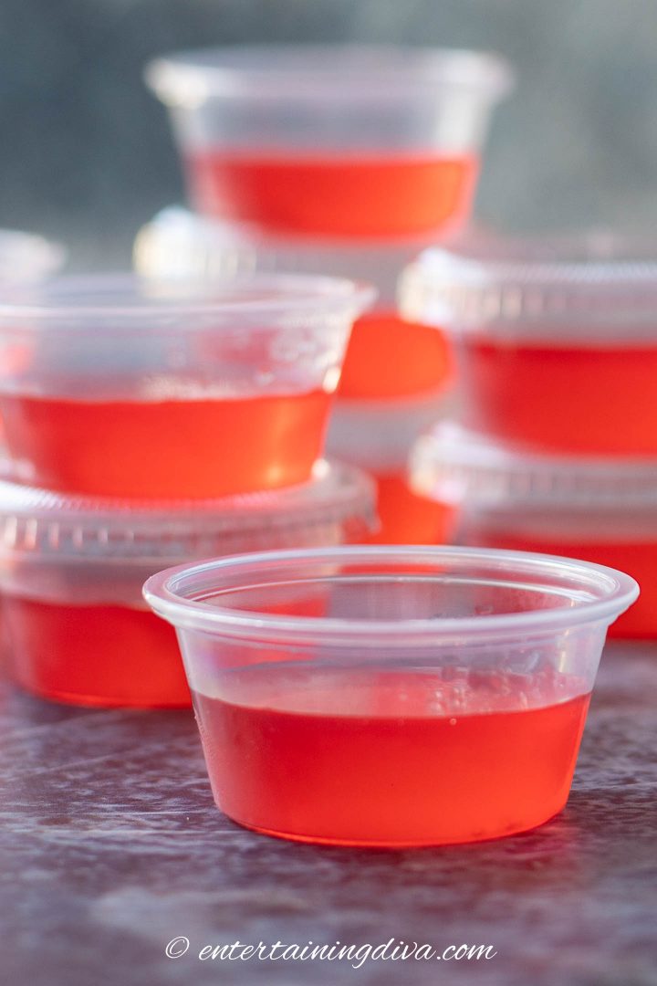 Close image of one watermelon jello shot with more in the background