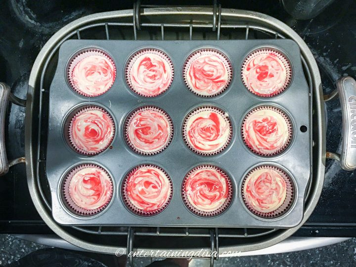 Mini raspberry cheesecake cupcakes in a muffin tin before baking in a roasting pan water bath