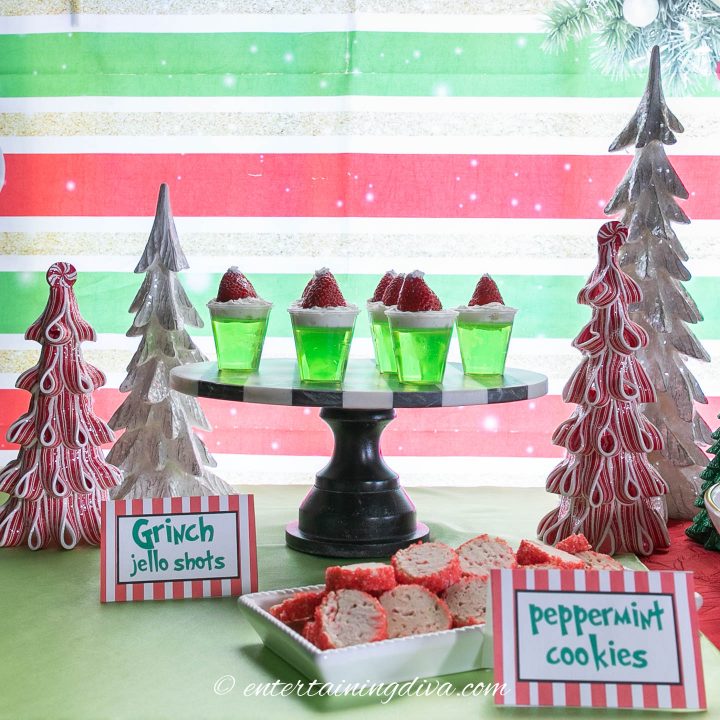 appletini jello shots with Santa hats made of strawberries and whipped cream on cake stand