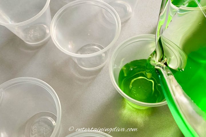 Jello shot mixture being poured in plastic cup
