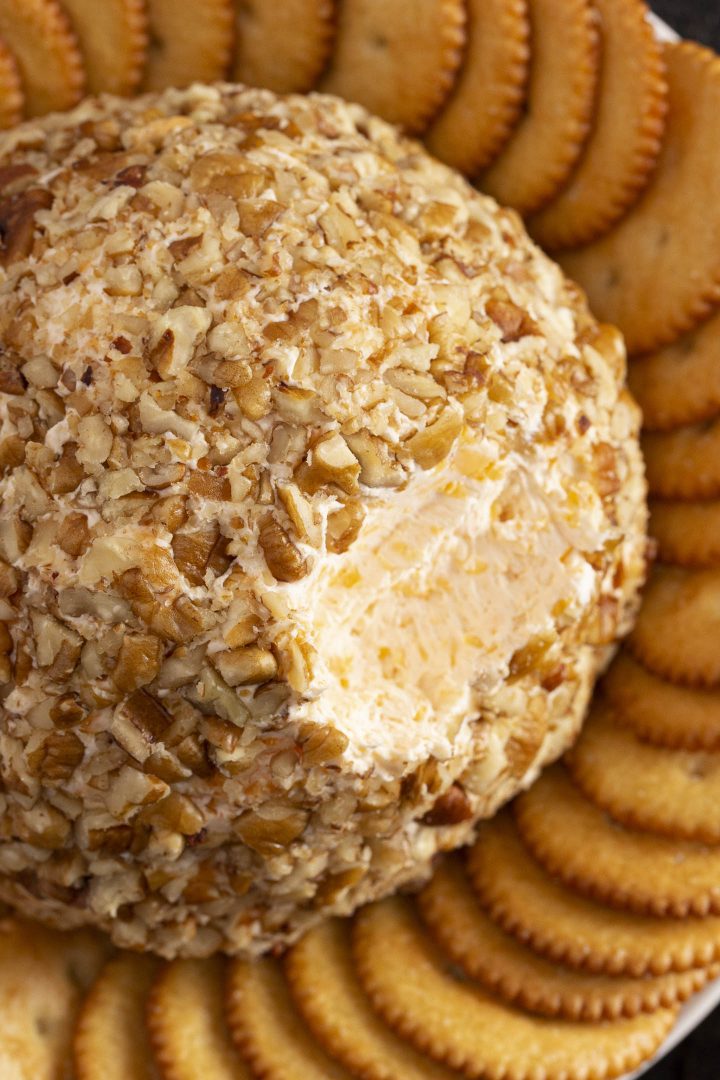Three cheese ball coated with nuts on a plate with crackers