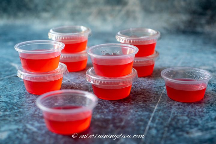 A stack of watermelon gelatin shots in shot cups with lids