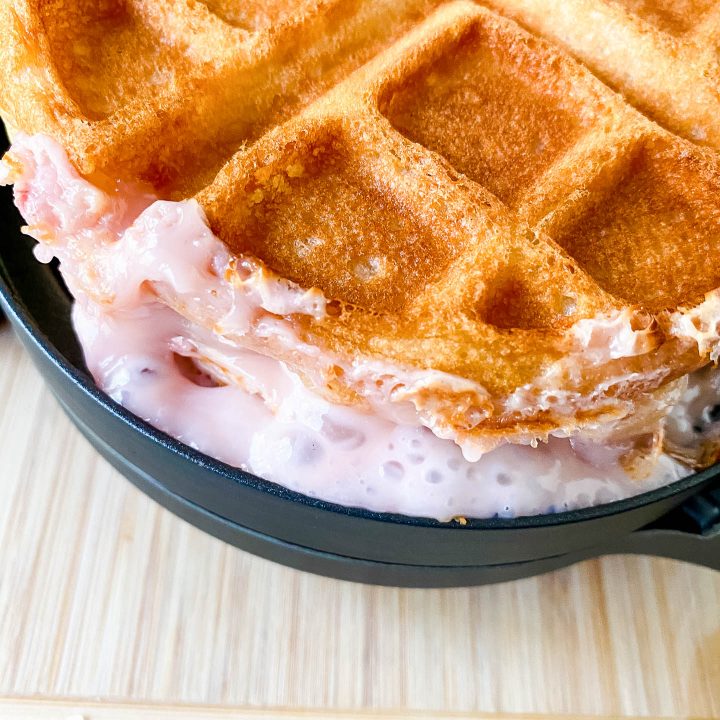 Strawberry cheesecake filling leaking out of a stuffed waffle