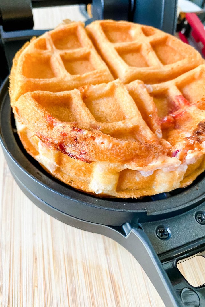 Cooked strawberry and cream cheese stuffed waffle being removed from the waffle iron