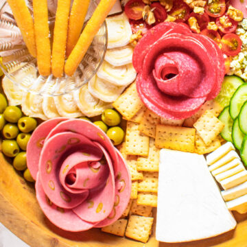 Charcuterie board with sliced meat shaped like roses