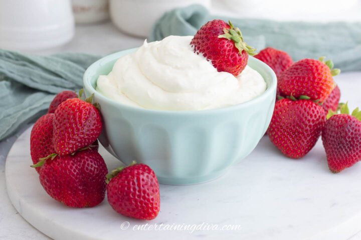 Fluffy cream cheese fruit dip with powdered sugar in a bowl with strawberries