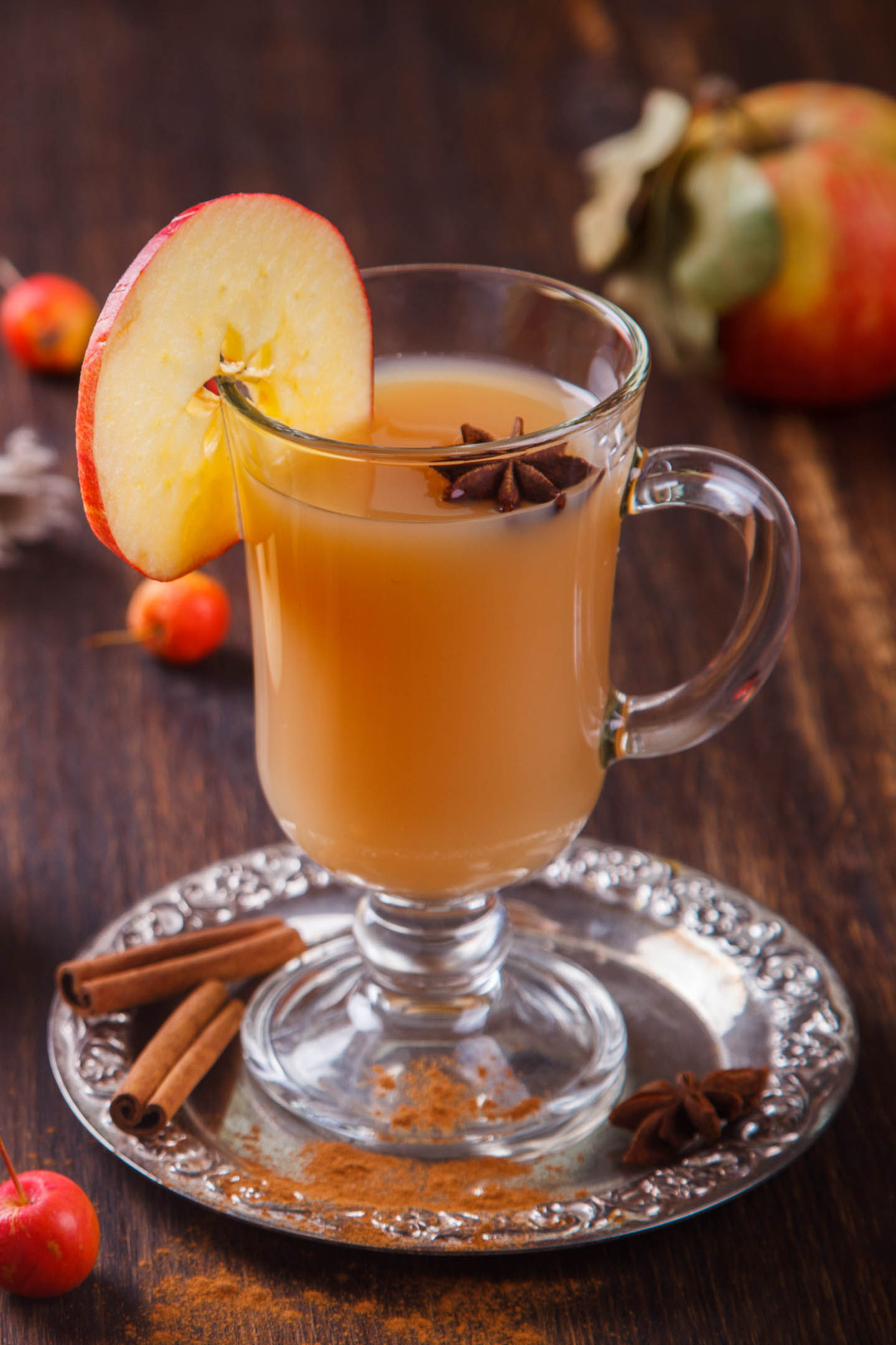 front view of glass of hot apple cider with spices and apple