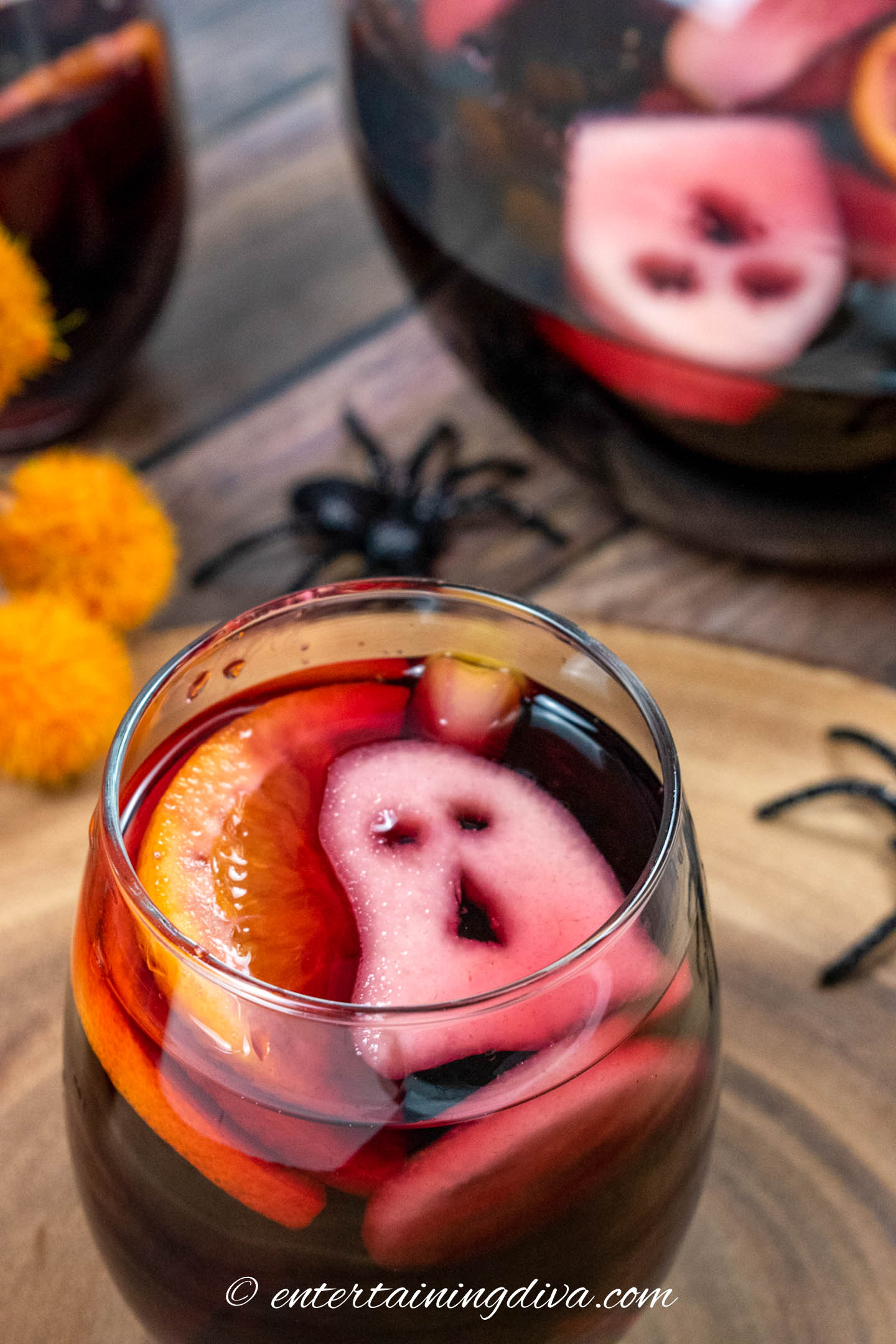 Spooky blackberry Halloween sangria in a glass with a ghost garnish and a pitcher in the background