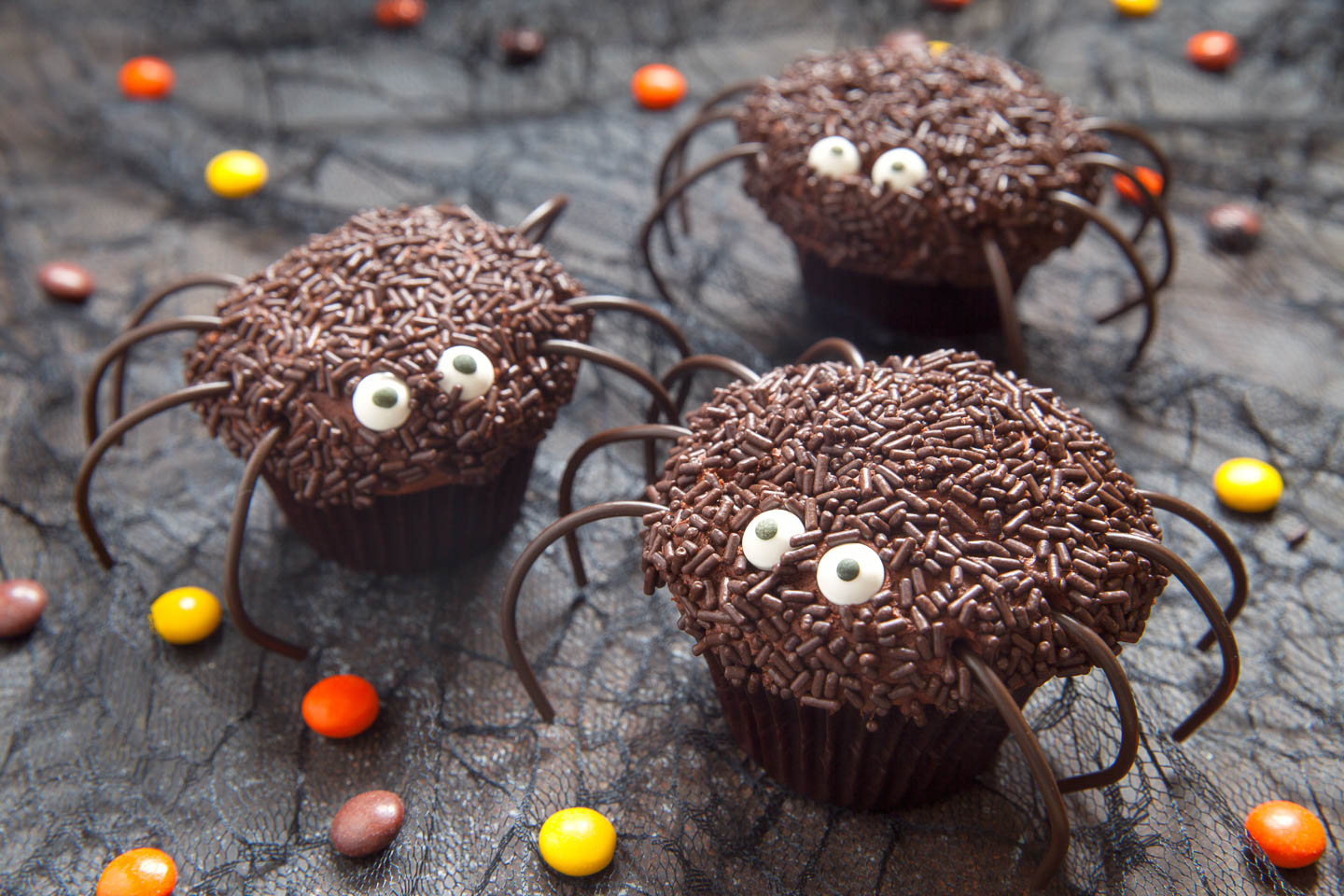 Chocolate spider cupcakes with chocolate sprinkles and black string licorice legs