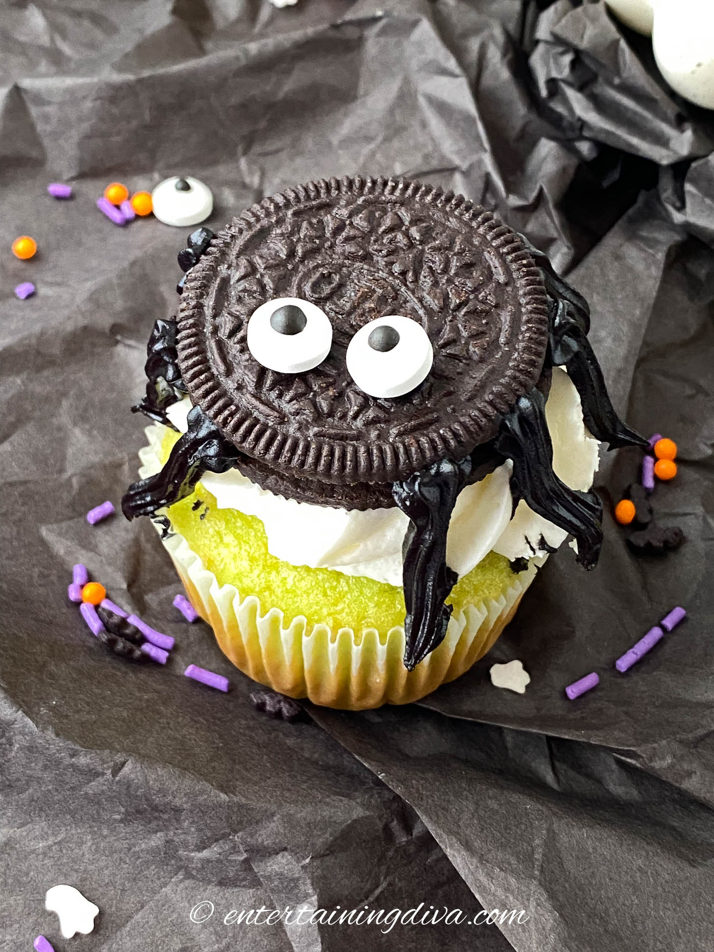 Oreo spider cookie on a black background with orange and purple sprinkles