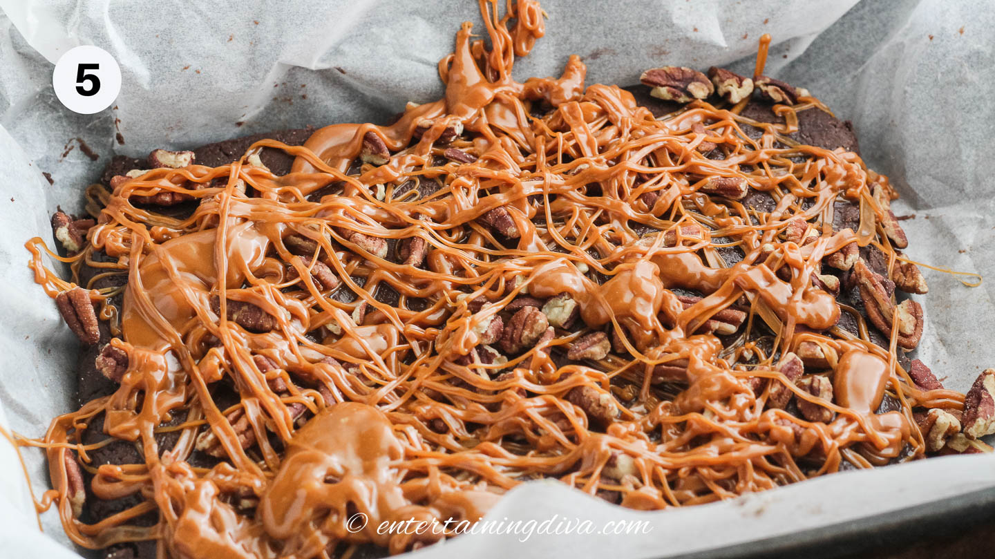 chocolate fudge with caramel sauce and pecans in a baking dish lined with parchment paper